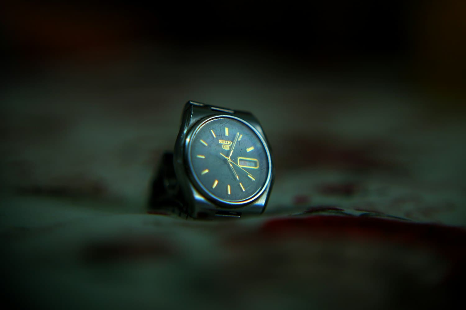 Watch with a deep cobalt-teal dial, softly lit